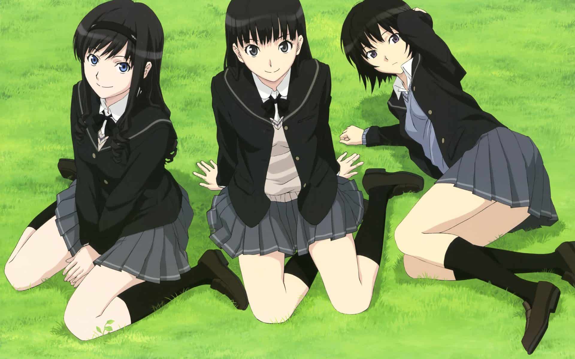 Three girls in school uniform posing on a grass field.