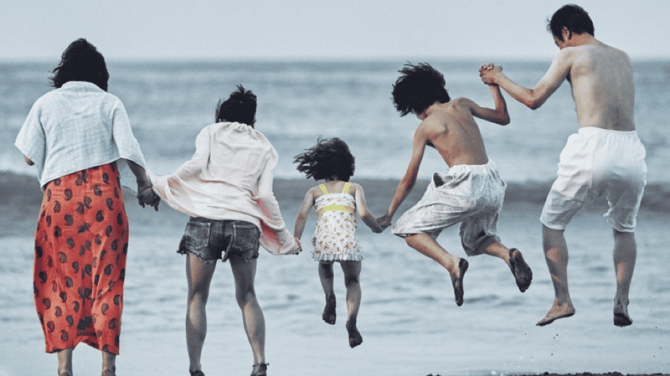 The family from the movie Shoplifters at a beach, all jumping in the air