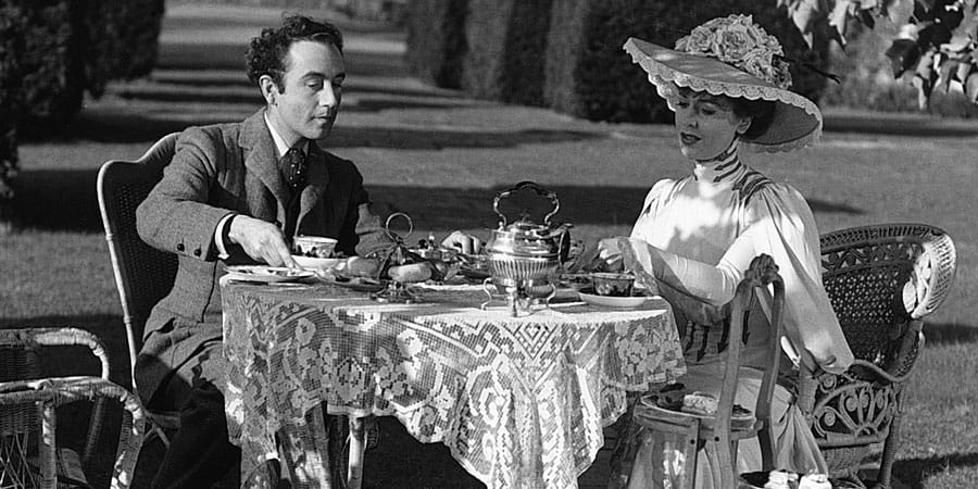 Characters from the movie Kind Hearts and Coronets sitting at a picnic table