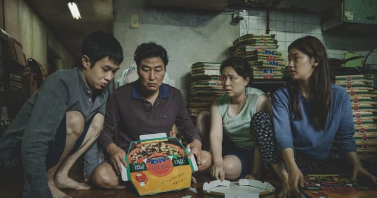 The Kim Family from the movie Parasite all gathered around empty Pizza boxes