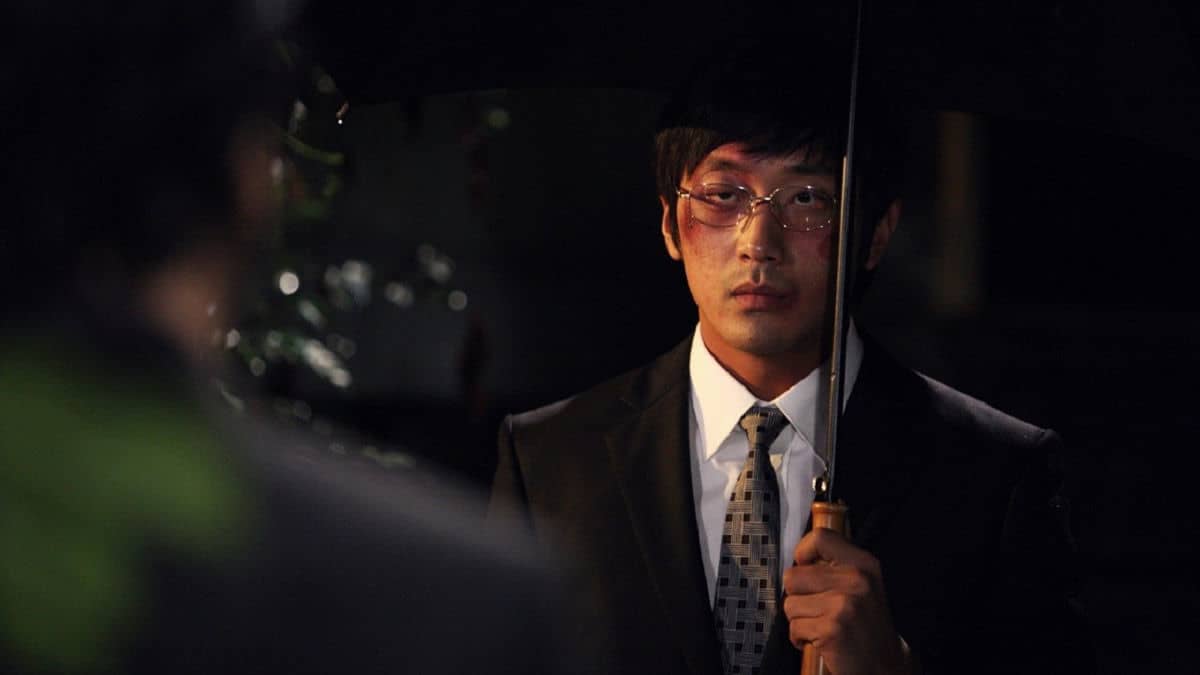 A character from the movie The Chaser standing under an umbrella
